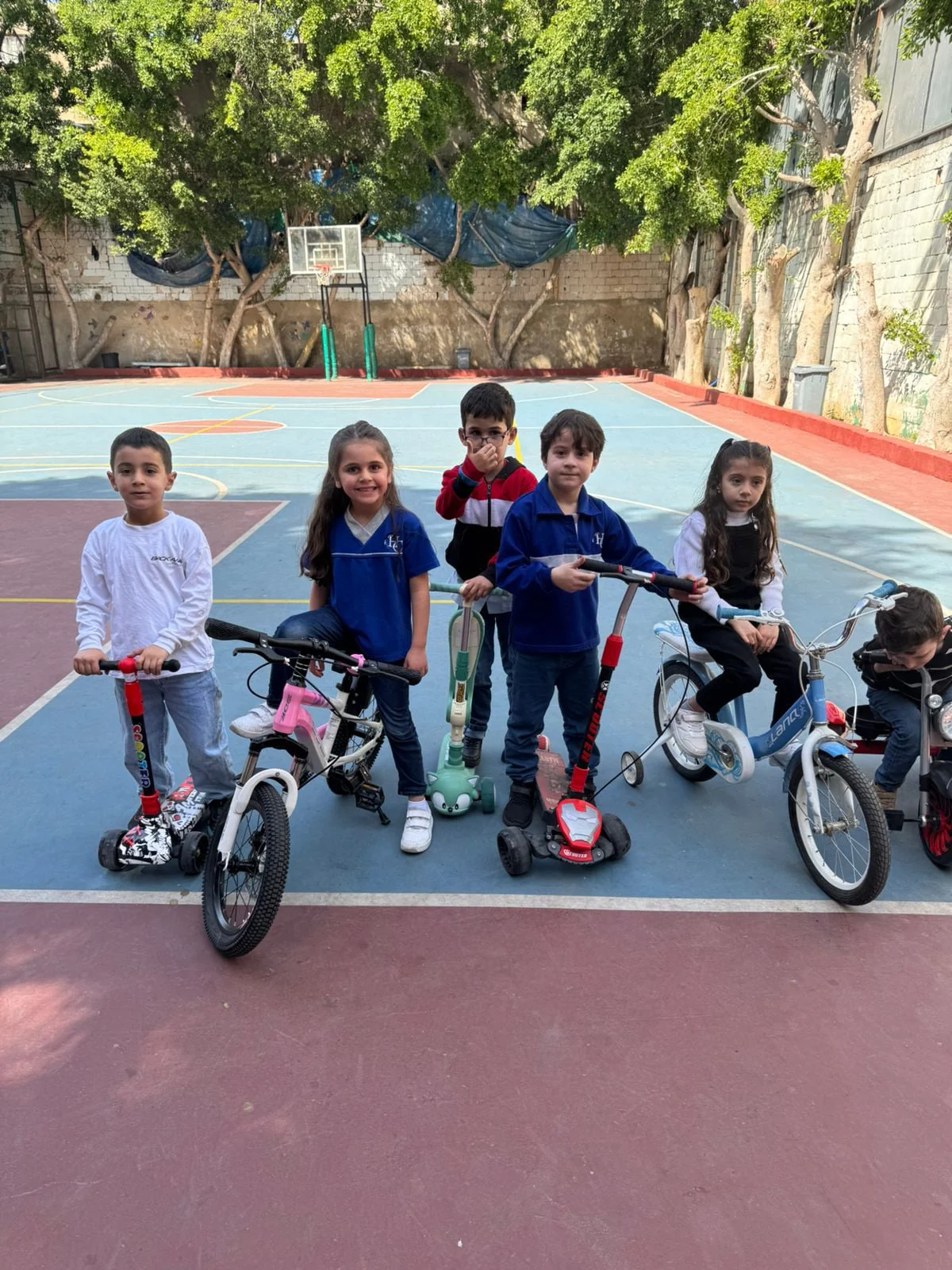 Students on bicycles and scooters on the school sports court