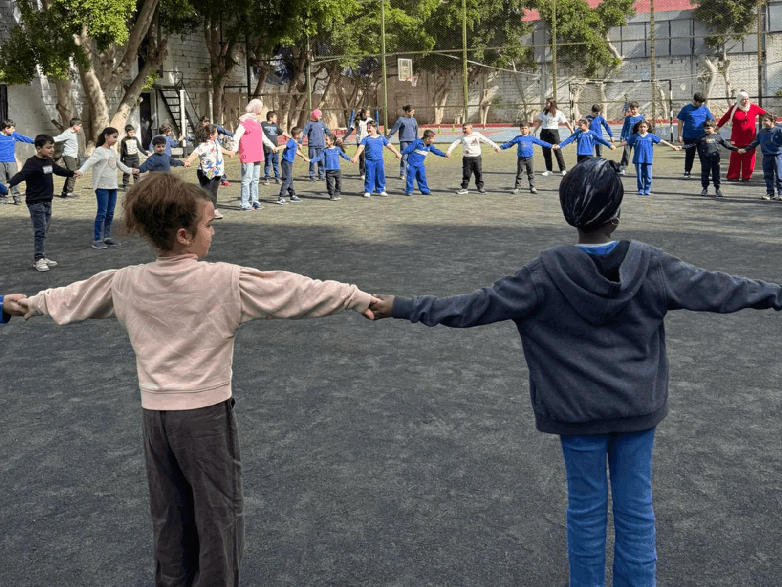 Children holding hands in a circle during a school outdoor activity