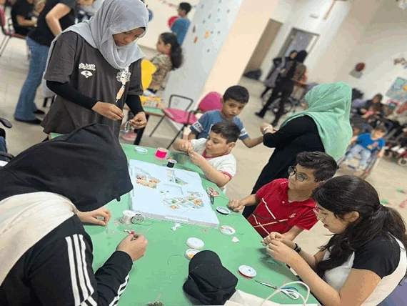 طلاب وبالغون يشاركون في نشاط حول طاولة خلال زيارة للخدمة المجتمعية